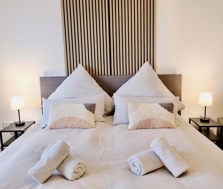 Liebevoll eingedecktes Bett mit Handtüchern vor Holzlamellen-Wand