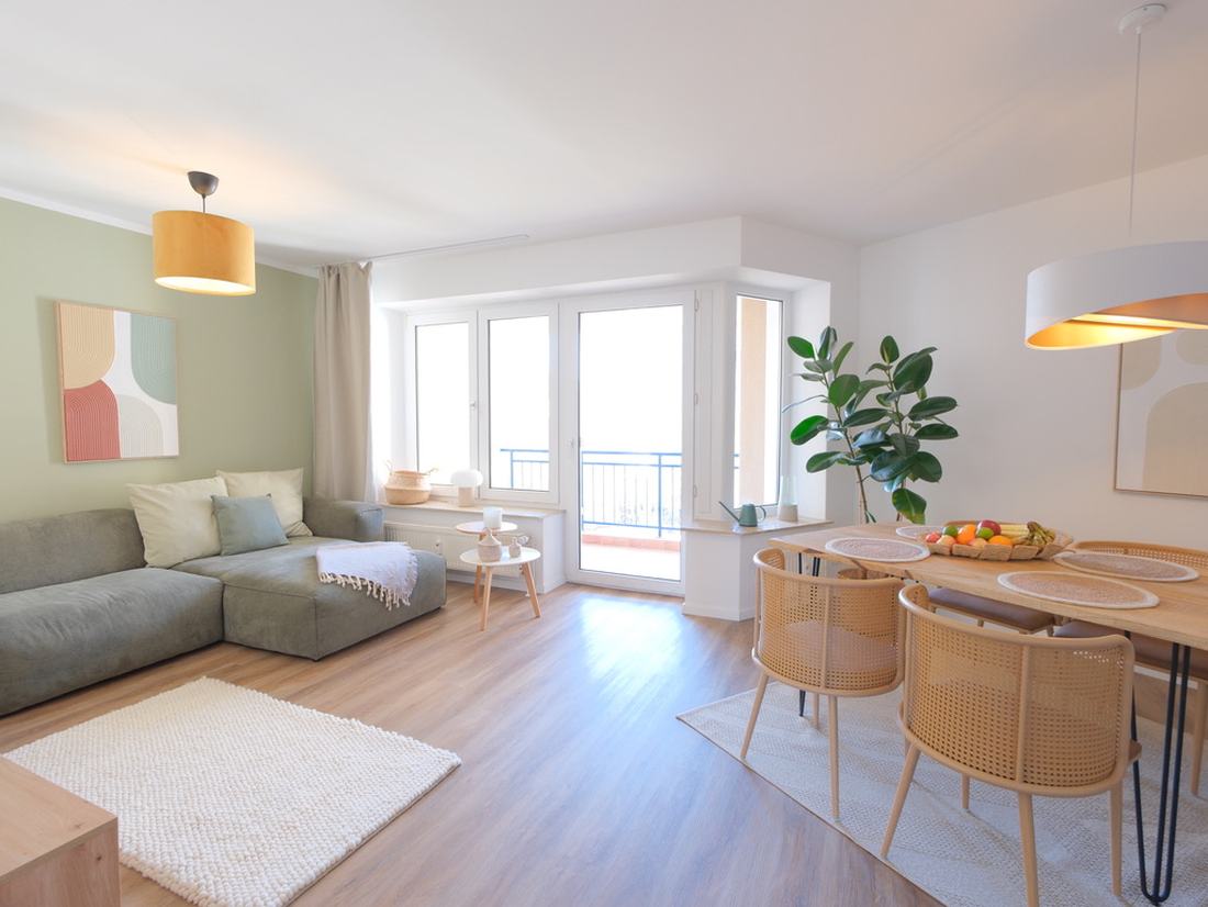 Offener Wohn- und Essbereich mit salbeigrüner Wand, Sofa, Balkon und Esstisch