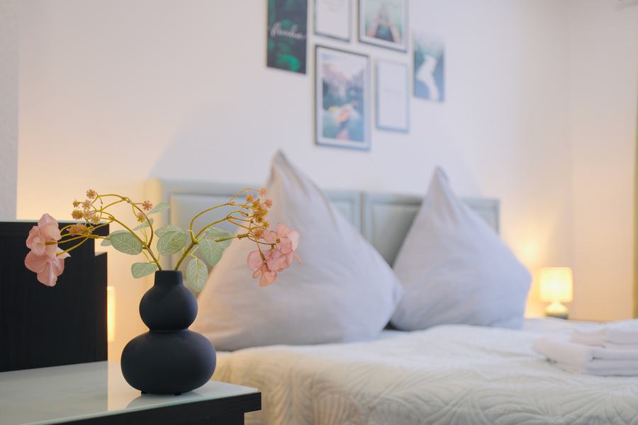 Bett-Detail mit weichen Kissen und Blumendeko